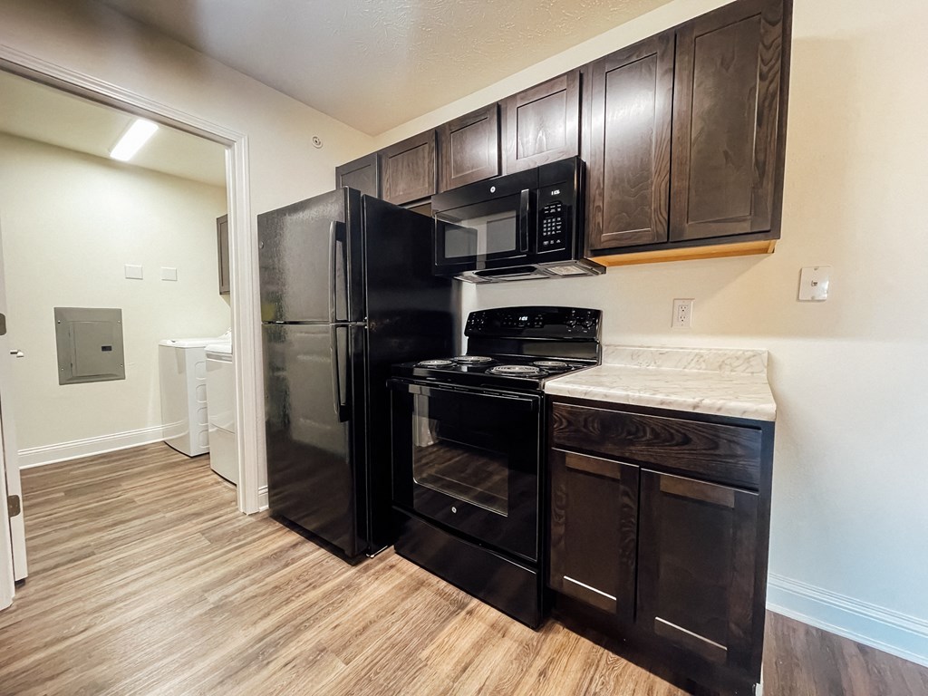 a kitchen with black appliances and wood flooring in a home