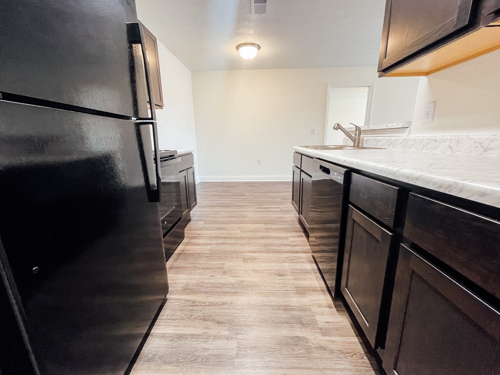 an empty kitchen with black appliances and a white counter top