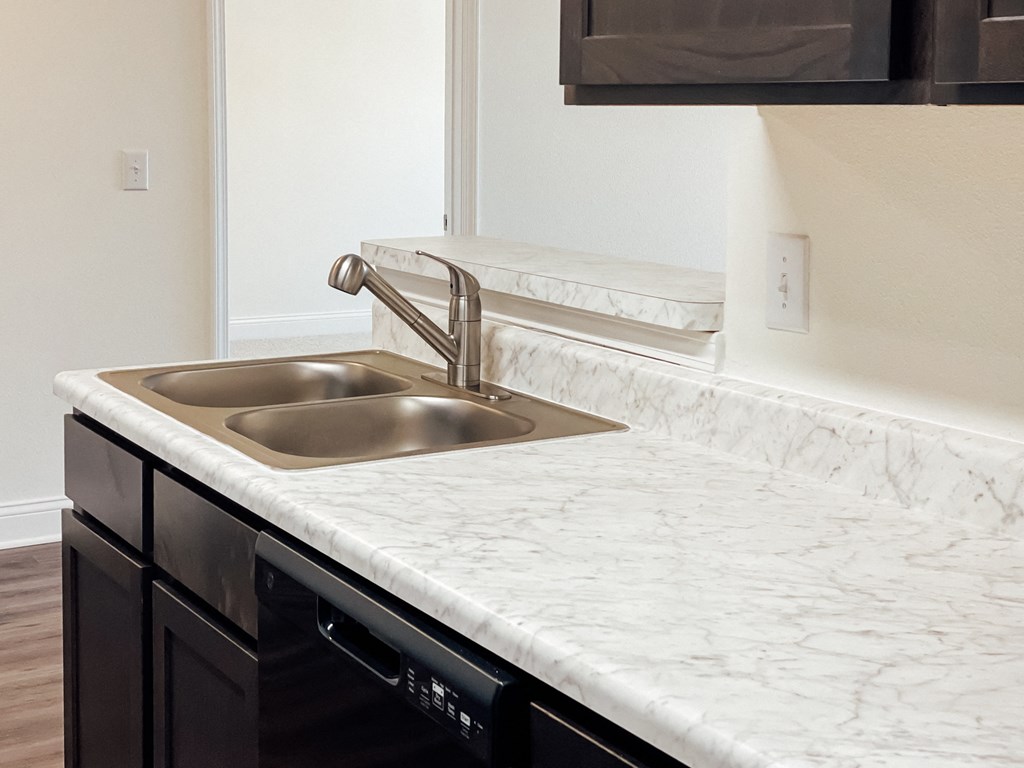 a kitchen with marble counter tops and a stainless steel sink