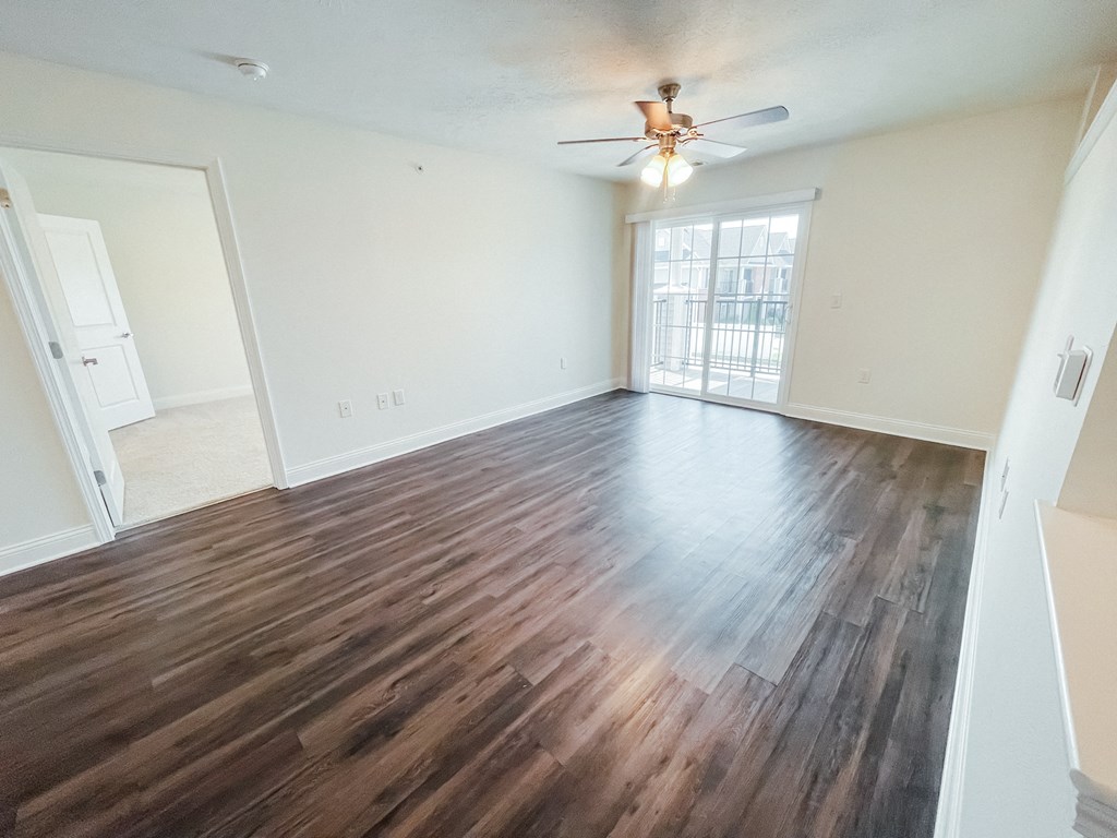 an empty living room with wooden floors and a ceiling fan