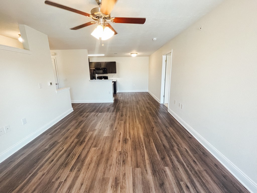 an empty living room with a ceiling fan and wood flooring