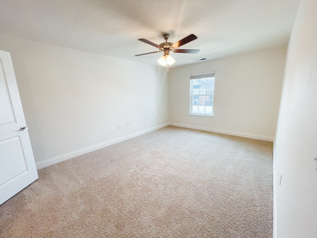 an empty living room with a ceiling fan and a window