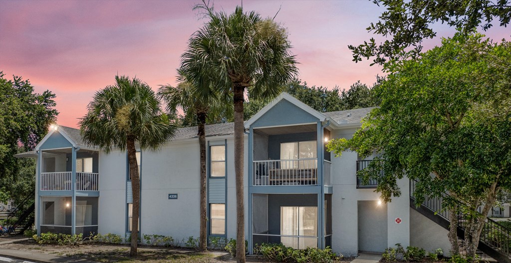 a building with two palm trees in front of it at Aqua Bay Apartments in Naples, FL 34116