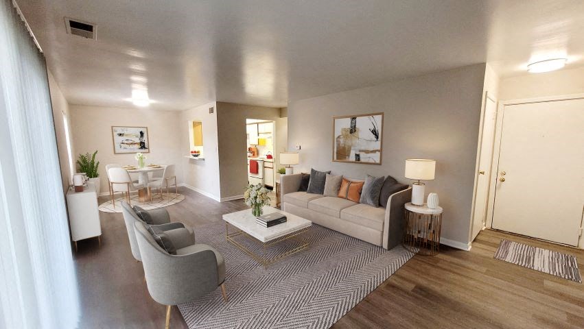 Spacious living room with a couch, coffee table, and 2 chairs next to the kitchen and dining area.  