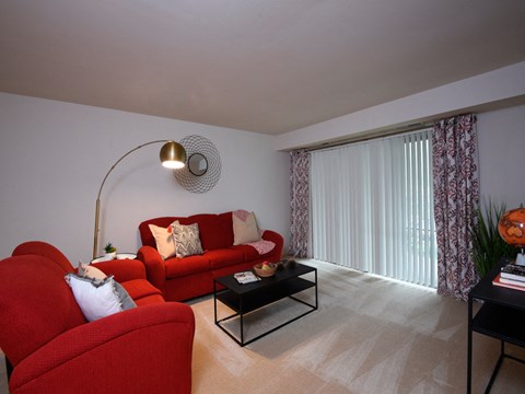 a living room with red couches and a table   and a large window