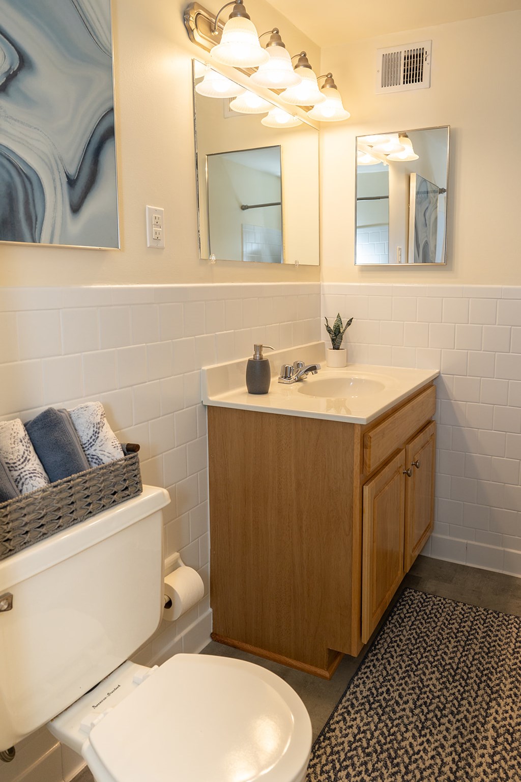 A bathroom with a toilet, sink, and mirror at Hyde Park Apartments*, Essex, MD 21221