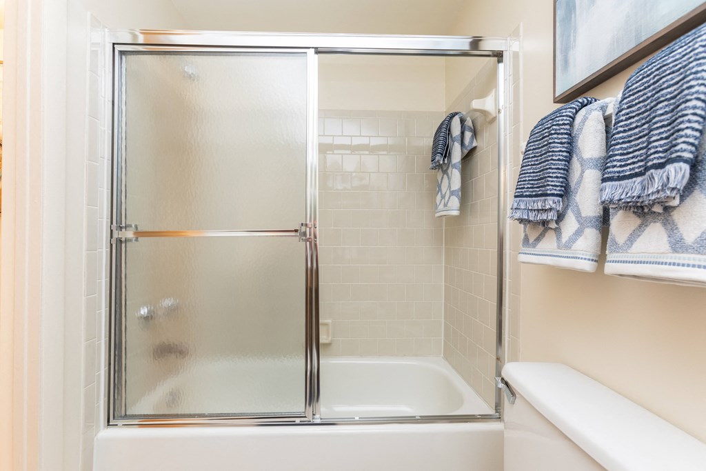 A small white bathroom with a glass shower door at Spring Hill Apartments & Townhomes, Baltimore