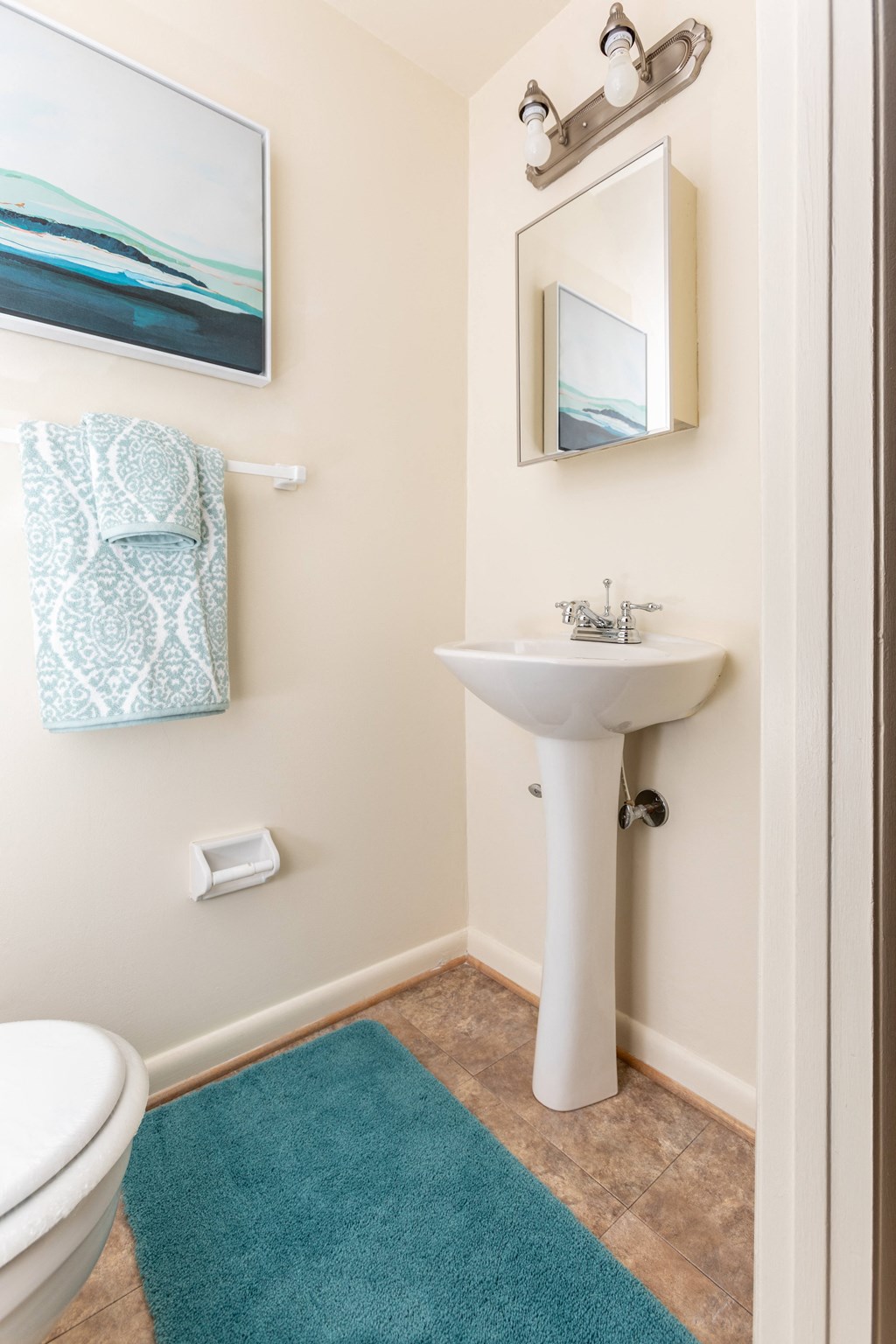 A bathroom with a white sink and a blue rug at Spring Hill Apartments & Townhomes, Baltimore