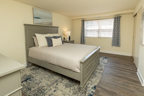 A bedroom with a large bed and a window with curtains at Colony Hill Apartments & Townhomes, Baltimore, MD