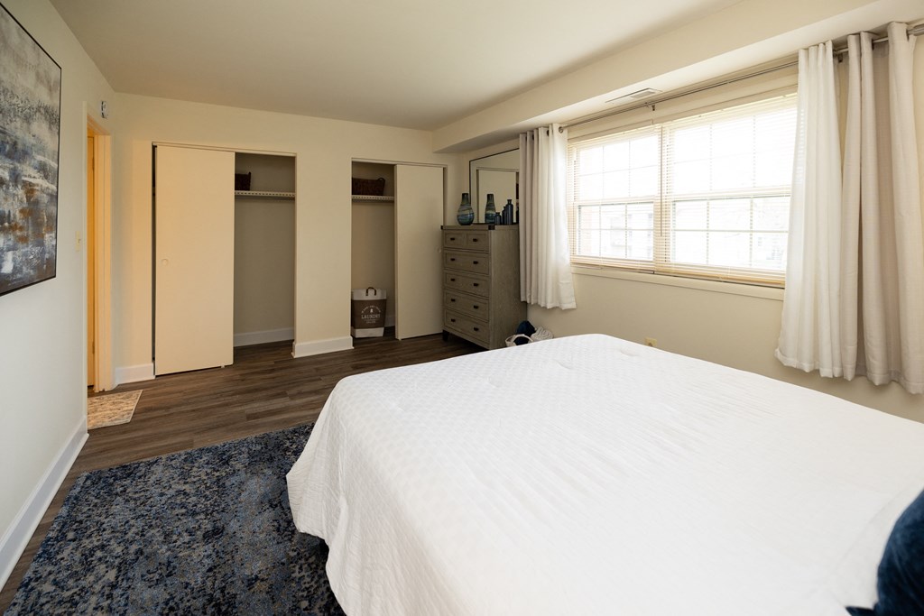 Bedroom with a white bed and a blue rug at Rockdale Gardens Apartments*, Baltimore, MD