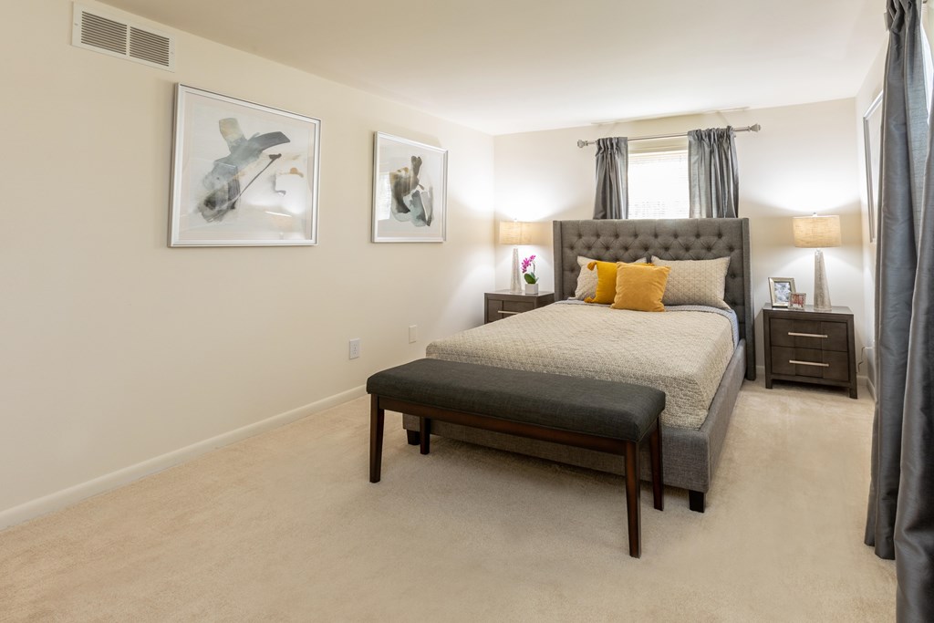 A bedroom with a large bed and two framed pictures on the wall at Spring Hill Apartments & Townhomes, Baltimore