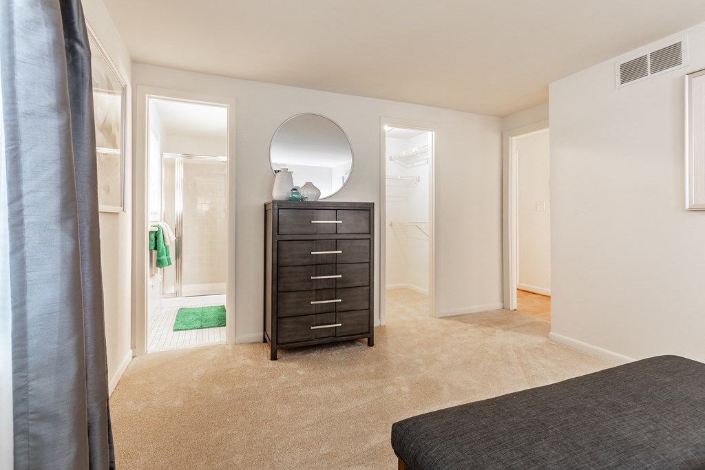 A bedroom with a black bed, a mirror, and a dresser at Spring Hill Apartments & Townhomes, Baltimore