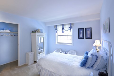 Bedroom with blue walls and a white bed with blue pillows at Painters Mill Apartments, Randallstown, 21117