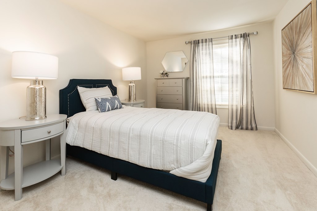 A bedroom with a large bed, a nightstand, and a dresser at Spring Hill Apartments & Townhomes, Baltimore