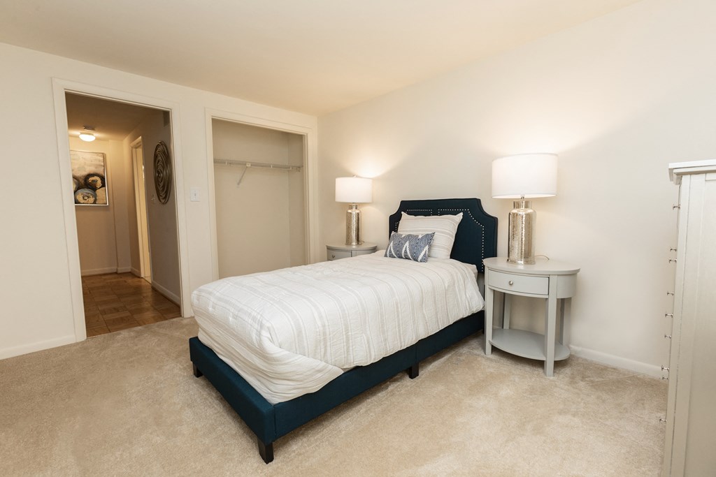 A bedroom with a bed, nightstand, and lamp at Spring Hill Apartments & Townhomes, Baltimore