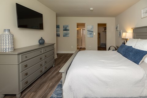 A bedroom with a large bed and a tv mounted on the wall.