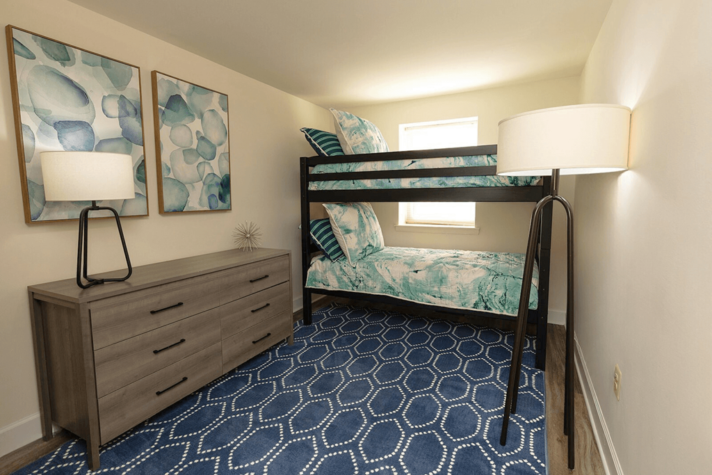 A room with a bunk bed, a dresser, and a patterned carpet.