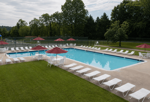 A large outdoor swimming pool surrounded by lawn chairs and umbrellas.