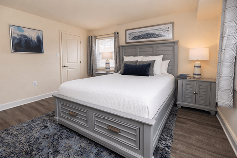 A bedroom with a large bed and a painting on the wall.