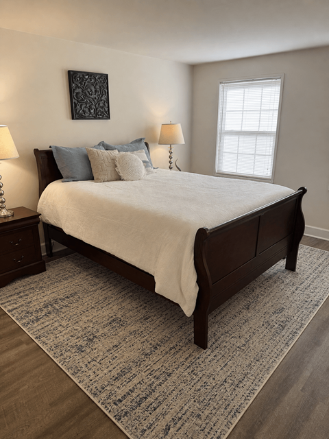 A bedroom with a large bed and a patterned rug.