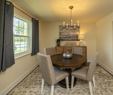 A dining room with a round table and chairs at The Brittany Apartments, Maryland