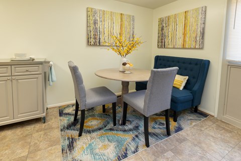 A dining room with a round table and grey chairs.