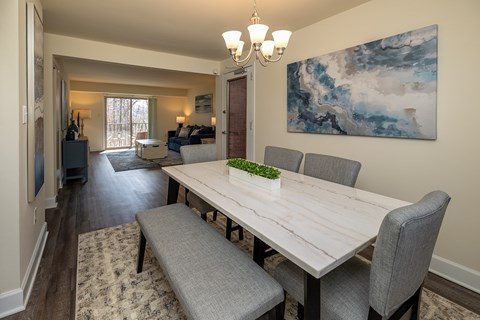 A dining room with a long table and grey chairs.