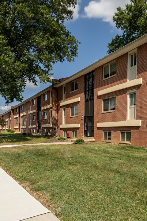 A long brick building with a green lawn in front at Winston Apartments, Baltimore, Maryland