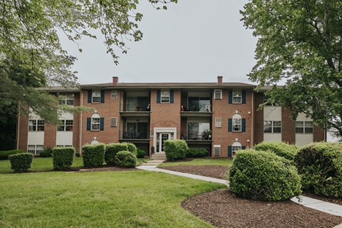 A brick building with green bushes in front at Deer Park Apartments, Randallstown, 21133