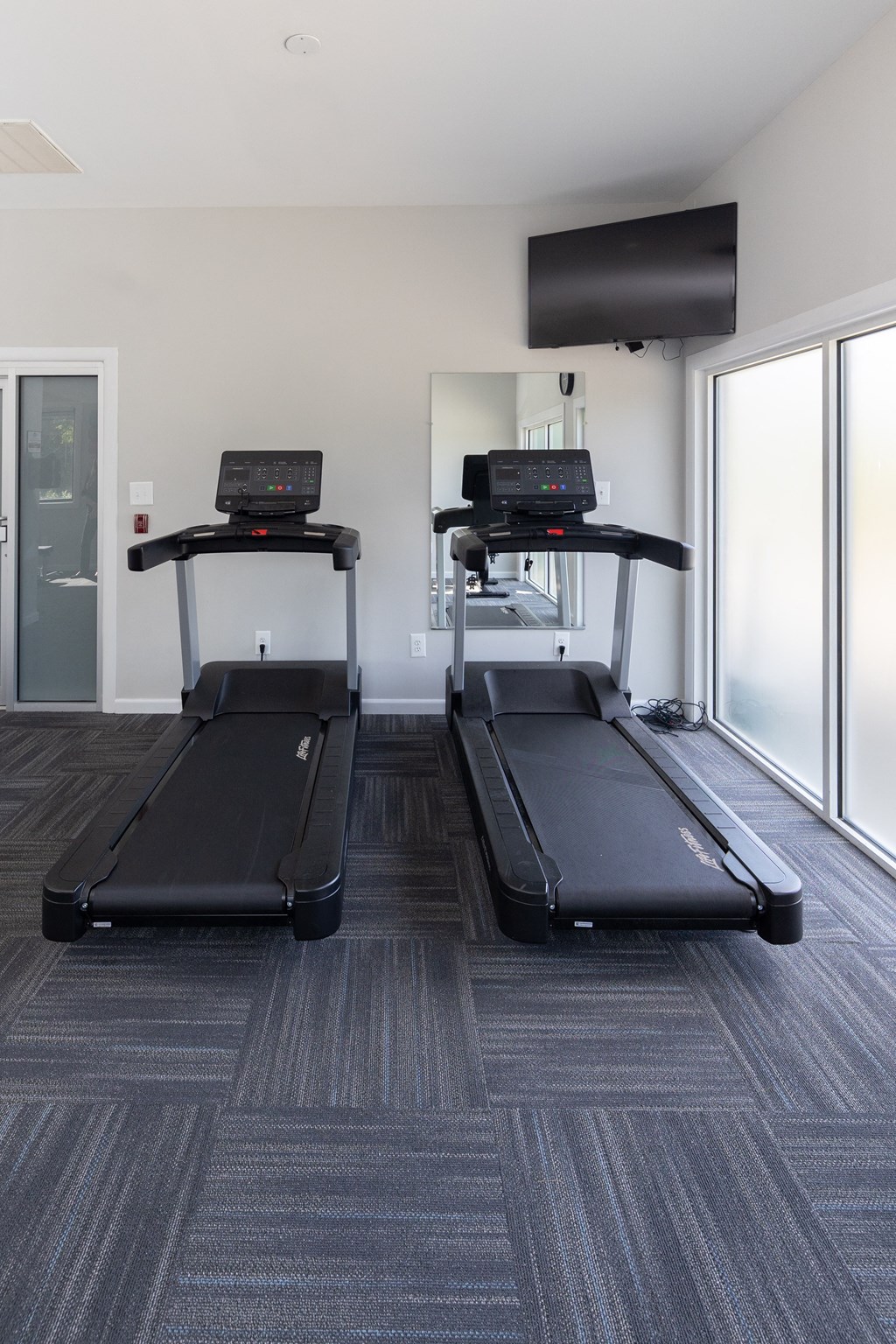 Two treadmills in a fitness room with a tv at Cromwell Valley Apartments, Towson