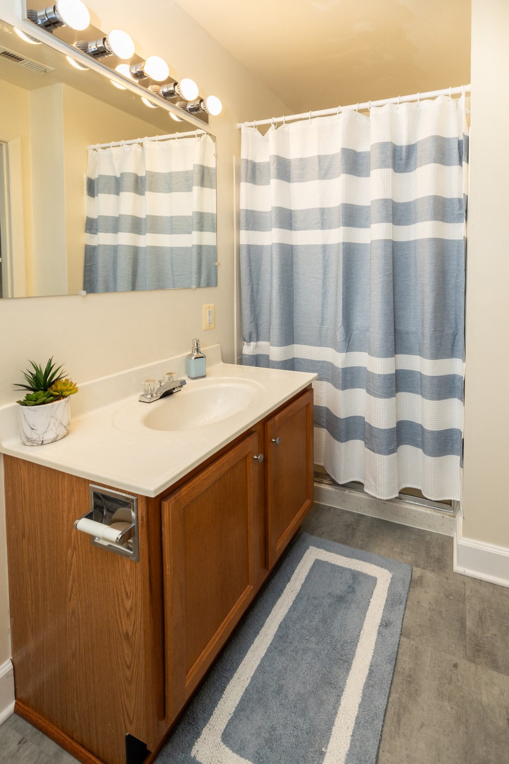a bathroom with a sink and shower and a blue and white shower curtain