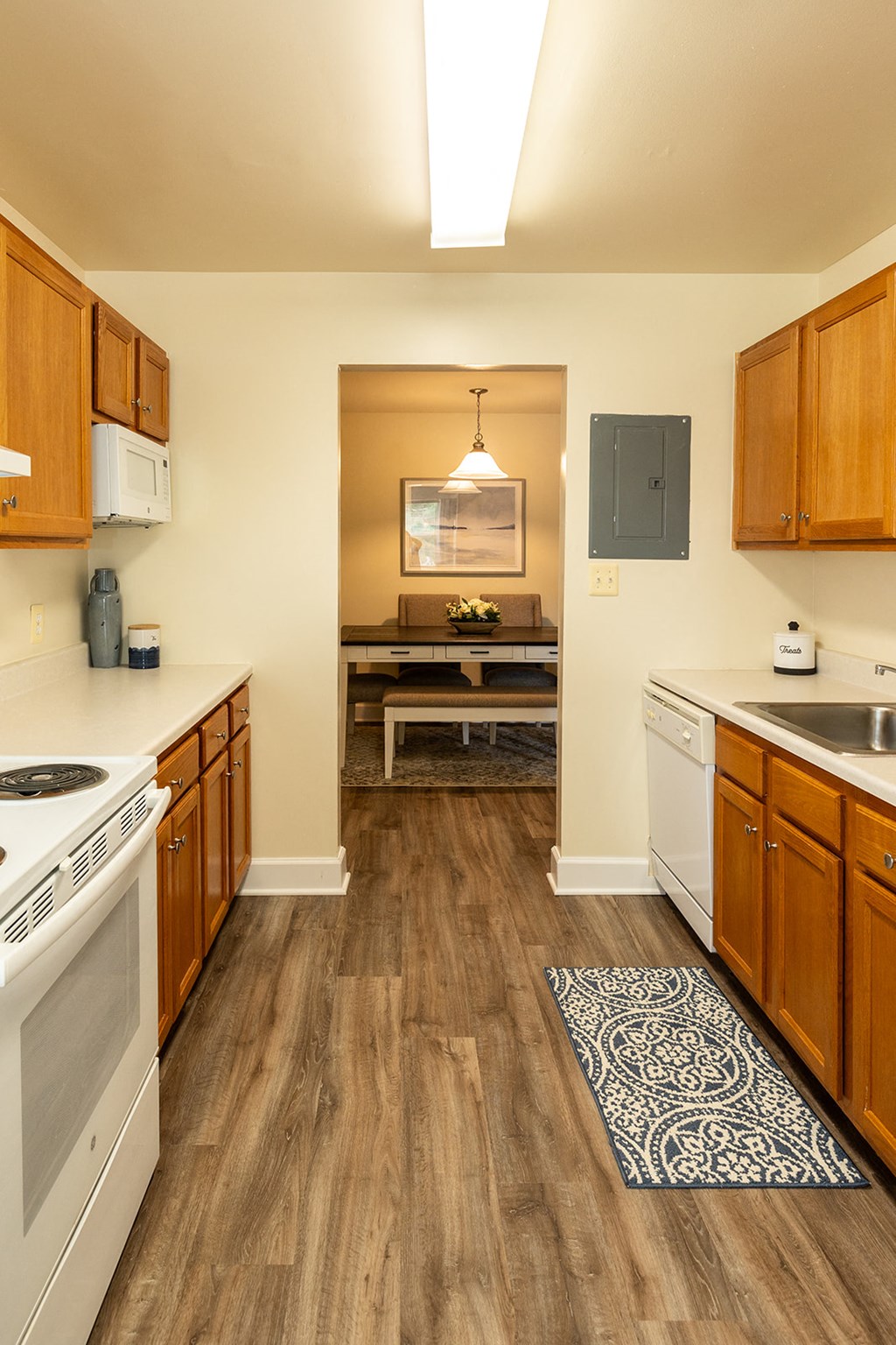 a kitchen with white appliances and wooden cabinets and a rug