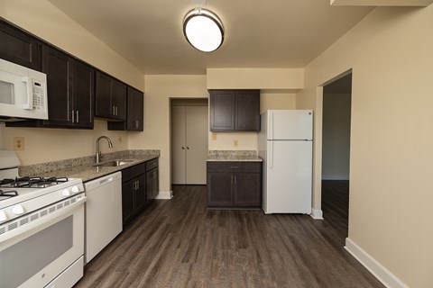 A kitchen with white appliances and dark brown cabinets at Lawyers Hill Apartments, Elkridge, 21075