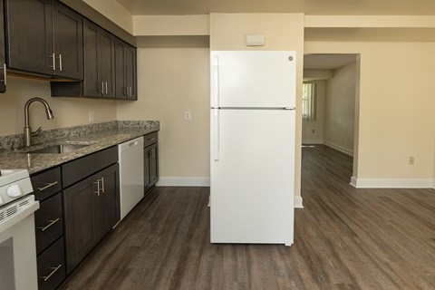 A white refrigerator in a kitchen with dark wood floors and cabinets at The Orchards at Severn Townhomes*, Severn, MD 21144.