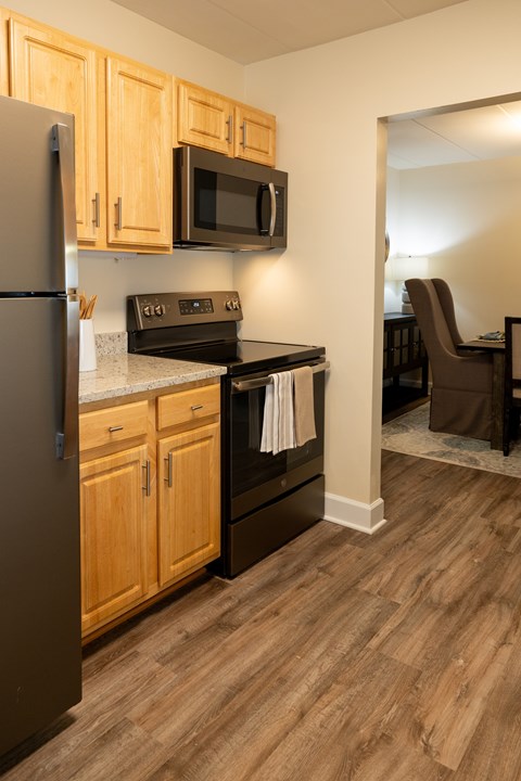 A kitchen with wooden cabinets and a black refrigerator.