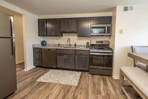 A kitchen with dark wood cabinets and a stainless steel refrigerator.
