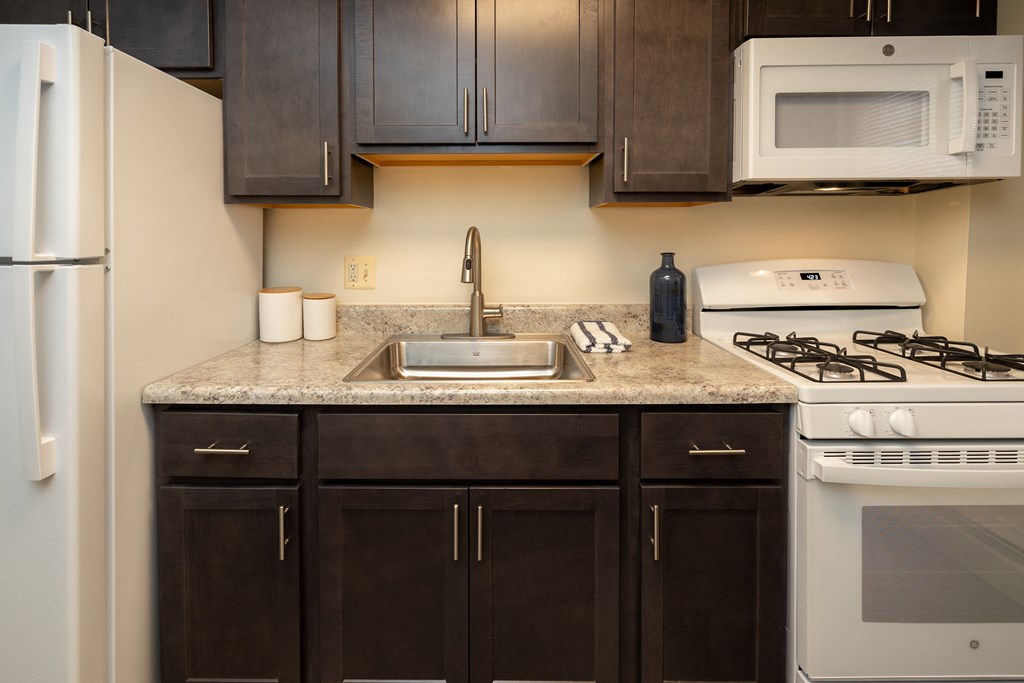 Kitchen with white appliances and black cabinets and granite counter tops at Loch Bend Apartments, Baltimore, Maryland. 