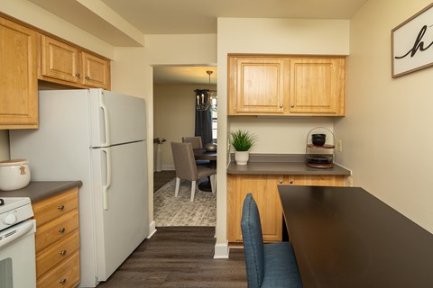A kitchen with a refrigerator, stove, and wooden cabinets.