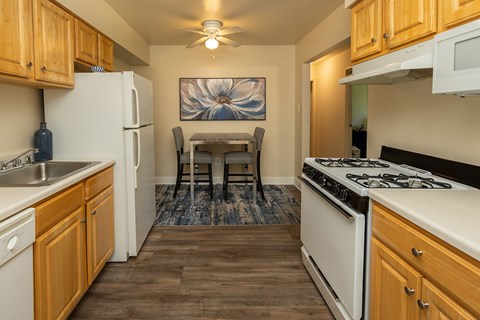 A kitchen with wooden cabinets and a white stove top oven.at Deer Park Apartments, Maryland, 21133