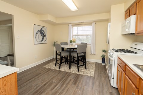 A kitchen with a dining table and chairs in the middle.