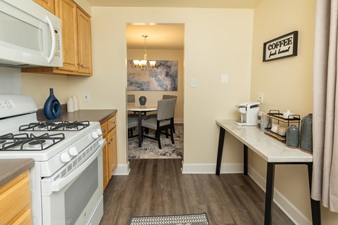 A kitchen with a white stove and a white microwave above it at Colony Hill Apartments & Townhomes, Baltimore, MD