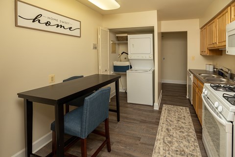 A kitchen with a table and chairs in front of a sign that says Home Sweet Home.