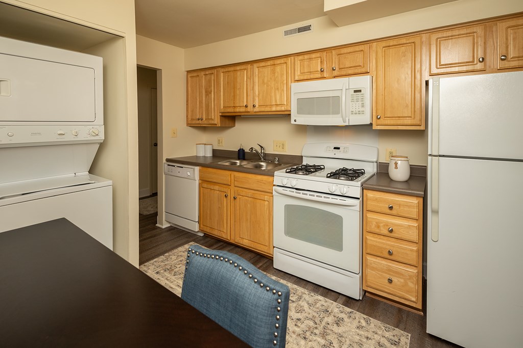 A kitchen with wooden cabinets and white appliances at The Brittany Apartments, MD