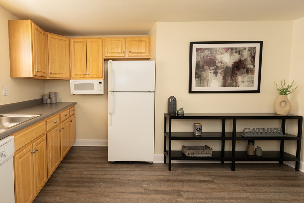 A kitchen with a white refrigerator and wooden cabinets at Hyde Park Apartments*, Essex, MD 21221