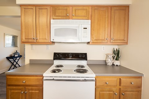 Wooden kitchen cabinets with white microwave and oven with gas range