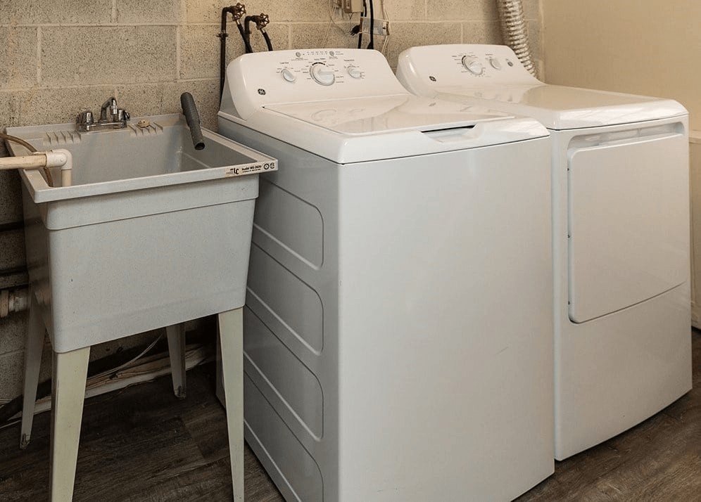 A white washing machine and sink in a laundry room.