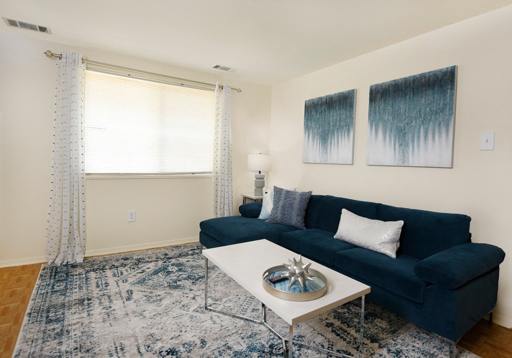 a living room with a blue couch and a coffee table at Winston Apartments, Baltimore, MD