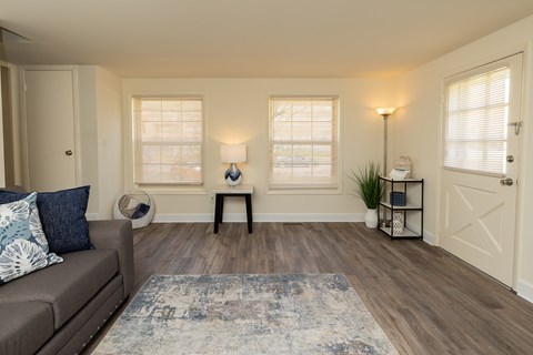 Living room with two windows and wood, vinyl flooring.