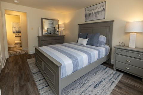A bedroom with a large bed and a painting on the wall.