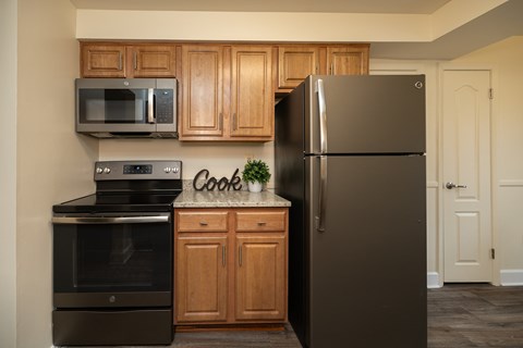 A kitchen with a black refrigerator, black oven, and black microwave.